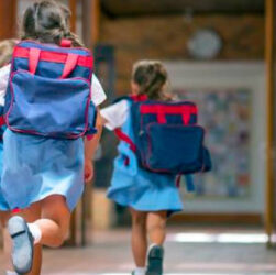 The kids in school uniforms are running to their classrooms with their backpacks. Back to school