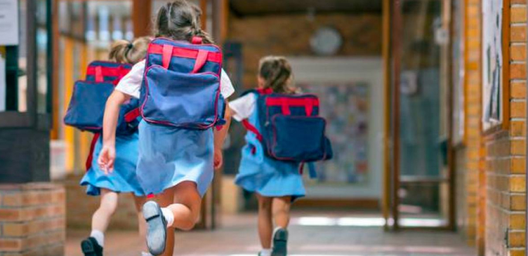 The kids in school uniforms are running to their classrooms with their backpacks. Back to school