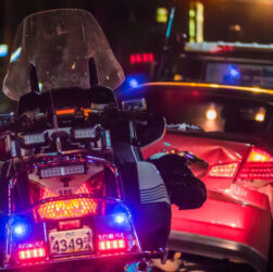 An accident scene, damaged car and traffic poice bike with lights on.