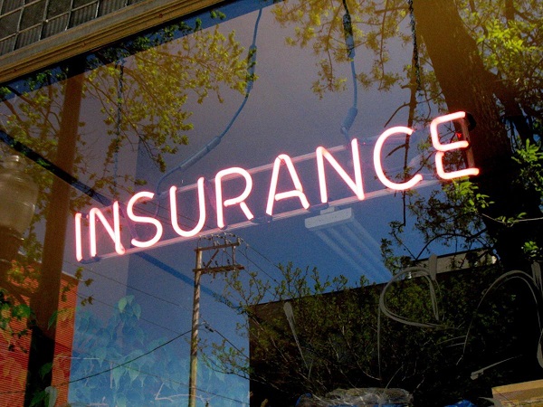 A glass window which has the word INSURANCE lighted up.